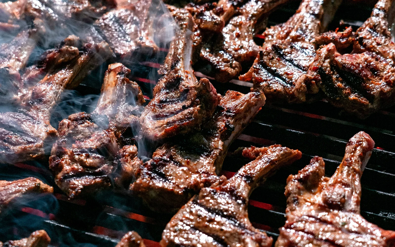Grilled meat cooking over an open flame on a barbecue grill (representative photograph of a braai-style grill, not the Nyama Choma buffet itself)